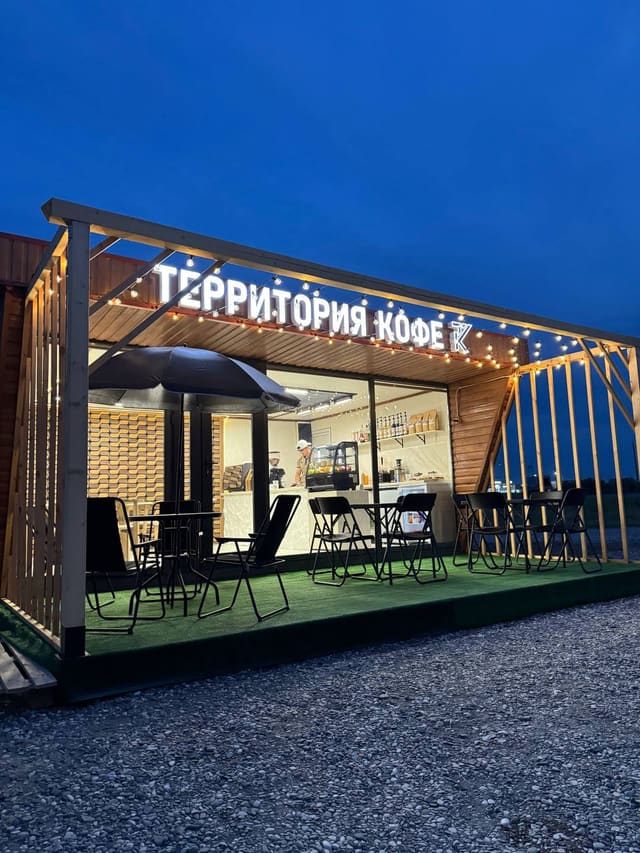 Кофейня «Территория кофе» вечером: светящаяся вывеска, гирлянды и терраса со столиками